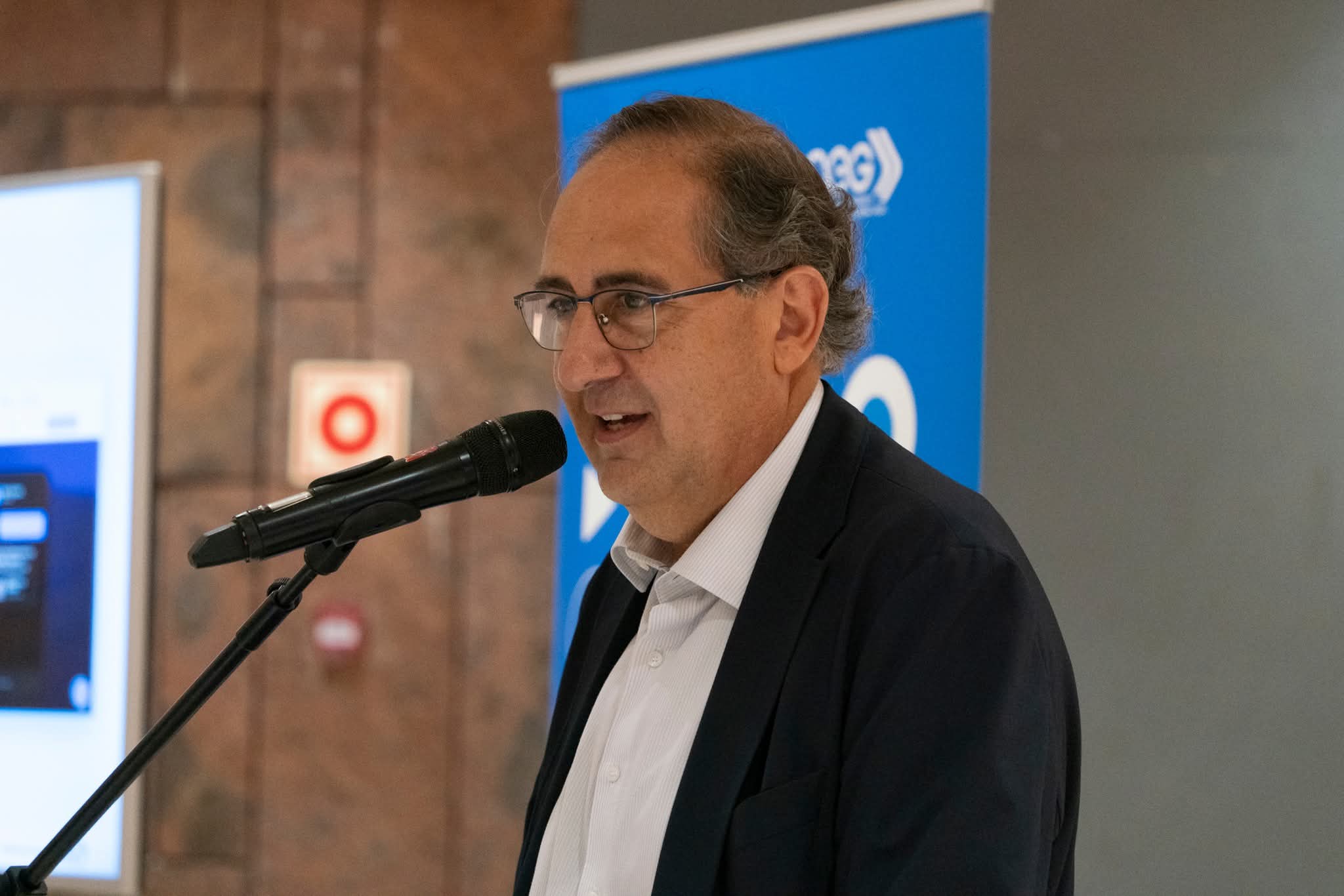 Ponente interviniendo ante el banner de la Asociación de Empresarios y Comerciantes de La Gomera